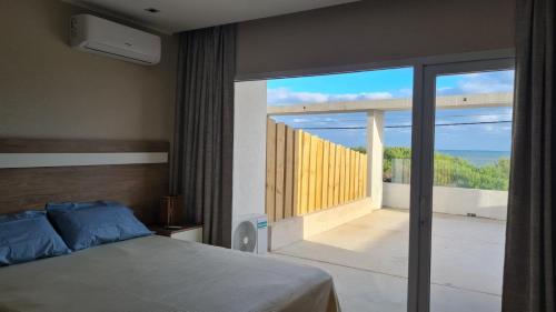 a bedroom with a bed and a large glass window at Departamento Las Olas con terraza frente al mar in Quequén