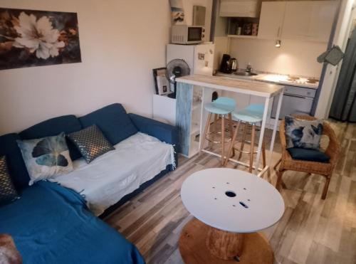 a living room with a blue couch and a table at Petit nid douillet in Argelès-sur-Mer