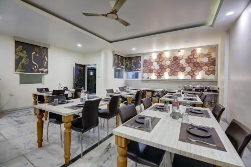 Un restaurante con mesas y sillas en una sala. en OPO Essential SKYNEX AEROCITY,Free airport Pickup and Drop, en Nueva Delhi
