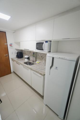 a white kitchen with a sink and a microwave at Gold flat praia de cabo branco in João Pessoa