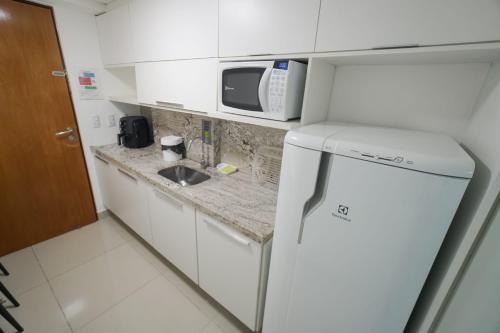a small kitchen with a microwave and a refrigerator at Gold flat praia de cabo branco in João Pessoa