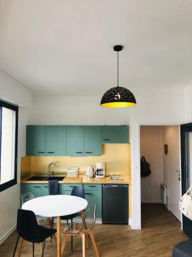 une cuisine avec des placards verts et une table avec des chaises dans l'établissement Studio bord de mer, à Les Sables-dʼOlonne