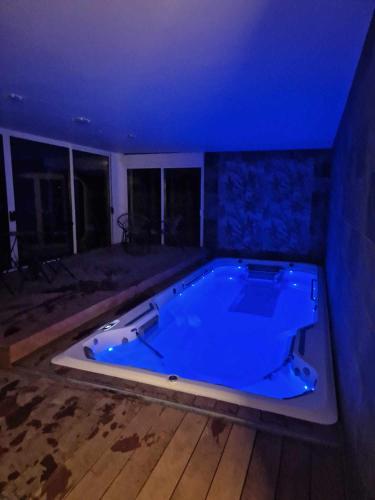 a large jacuzzi tub in a room with blue lighting at Escapade Romantique à Saint Omer-Espace Totalement Privatisé Avec Terrasse in Saint-Omer