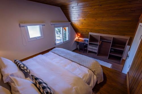 a bedroom with a bed in a room with wooden walls at Zur Suítes in Campos do Jordão