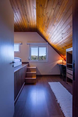 a bedroom with a wooden ceiling with a bed and a window at Zur Suítes in Campos do Jordão