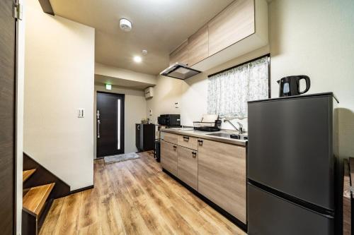 a kitchen with a black refrigerator and wooden floors at 72, Nakanobu A, Entire house for rent, 中延A in Tokyo
