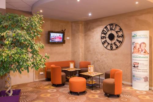 a waiting room with orange chairs and a clock at Brit Hotel Tours Sud – Le Cheops in Joue-les-Tours