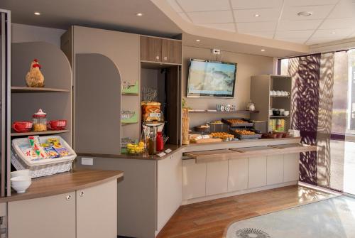 a kitchen with a counter with a refrigerator at Brit Hotel Tours Sud – Le Cheops in Joue-les-Tours