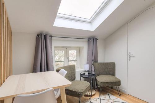 une chambre avec une table, des chaises et une lucarne dans l'établissement Appartement neuf, clim et parking, Caluire-Rhône, à Caluire-et-Cuire