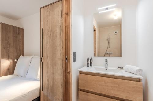 une salle de bain avec un lavabo, un lit et un miroir dans l'établissement Alpage Mont Blanc, à Combloux