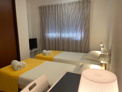 a hotel room with two beds and a television at Residencial Mar e Sol in Costa da Caparica