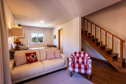 a living room with a couch and a staircase at Zur Suítes in Campos do Jordão