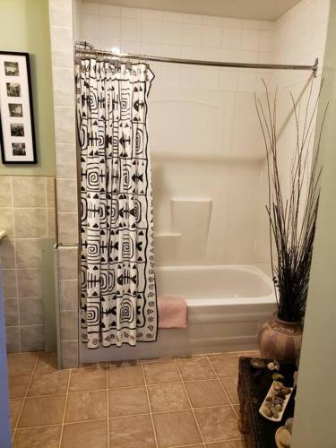 a bathroom with a tub and a shower curtain at Mission Historical Home in Calgary