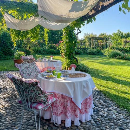 a table and chairs under a canopy in a garden at Maso Di Villa Relais di Campagna in Susegana