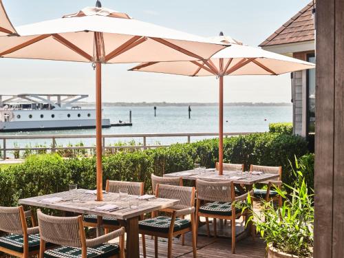 two tables and chairs with umbrellas in front of the ocean at Montauk Yacht Club in Montauk