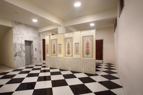 a room with a checkered floor and paintings on the walls at Hotel Bhakti Dhama in Vrindāvan