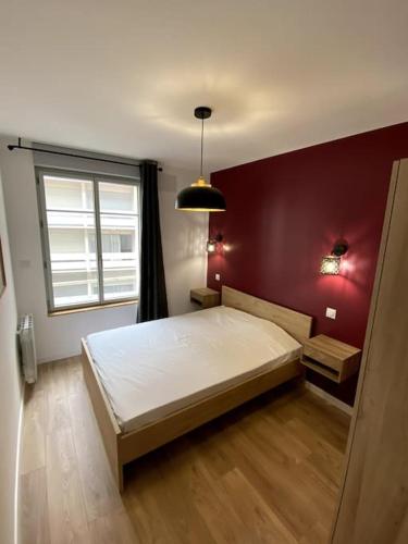 une chambre avec un lit et un mur rouge dans l'établissement Madonna Élégance, proche sanctuaire, 95m2, à Lourdes