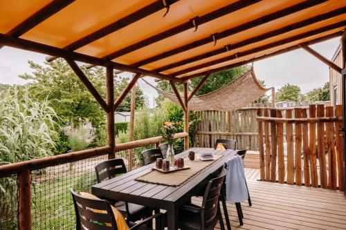 une terrasse en bois avec une table et des chaises dessus dans l'établissement Slow Village Pornic, à La Plaine-sur-Mer