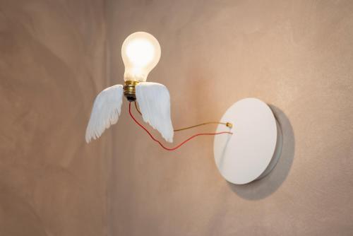 a light with wings and a light bulb on a wall at Guadalupe Tuscany Resort in Braccagni