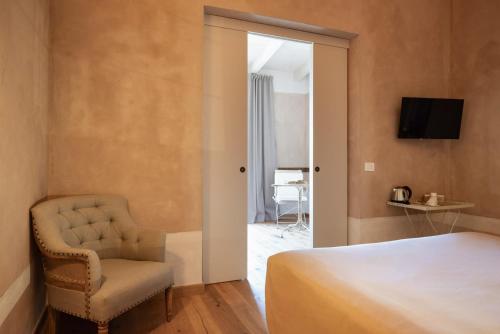 a bedroom with a bed and a chair and a television at Guadalupe Tuscany Resort in Braccagni