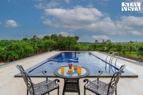 a patio with a table and chairs next to a swimming pool at StayVista at Terracotta Skies with Courtyard & Pool in Nashik