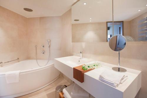 a bathroom with a sink and a tub and a mirror at Hotel Dubrovnik Palace in Dubrovnik