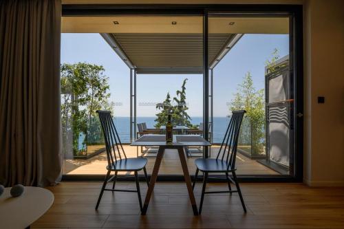 a dining room with a table and chairs and a large window at Mani Suites in Agios Nikolaos