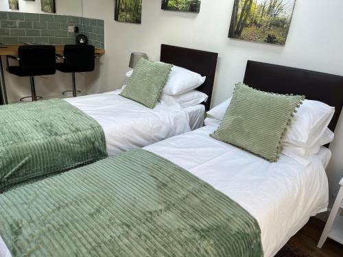 two beds with green and white pillows in a room at Little Hawthorns in New Alresford