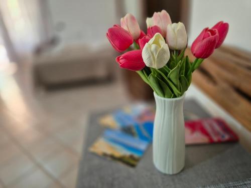 a white vase filled with pink and white flowers at RELAX MAREMONTI Ampia e Panoramica con spaziosa Veranda Attrezzata in Capoterra