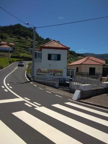 a car driving down a road next to a house at Casa Gama in Ribeira da Janela