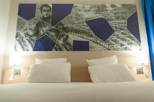 a bedroom with two white pillows and a painting on the wall at Brit Hotel M&acirc;con Centre Gare in M&acirc;con