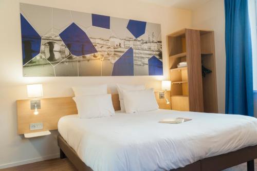 a bedroom with a large bed with white sheets at Brit Hotel M&acirc;con Centre Gare in M&acirc;con