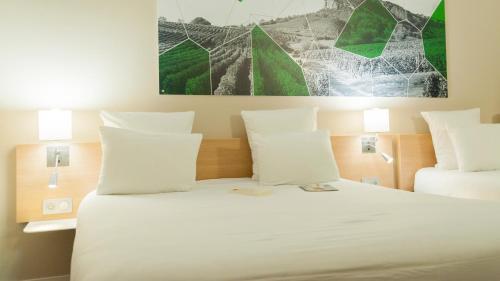 a bedroom with a bed with white sheets and pillows at Brit Hotel Mâcon Centre Gare in Mâcon