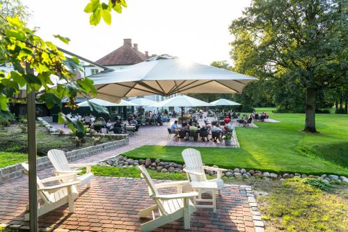a group of people sitting under an umbrella in a park at Hotel Gut Kaden in Alveslohe