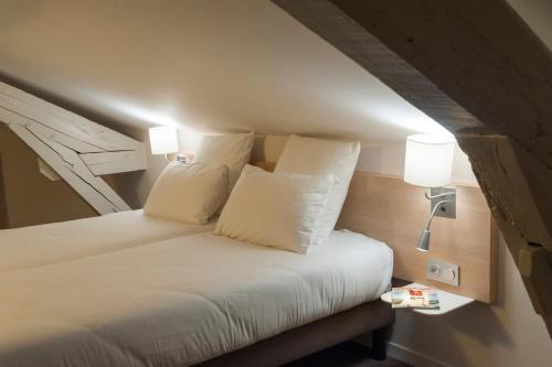 a bedroom with a bed with white sheets and pillows at Brit Hotel Mâcon Centre Gare in Mâcon