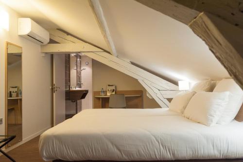 a bedroom with a white bed in a attic at Brit Hotel Mâcon Centre Gare in Mâcon
