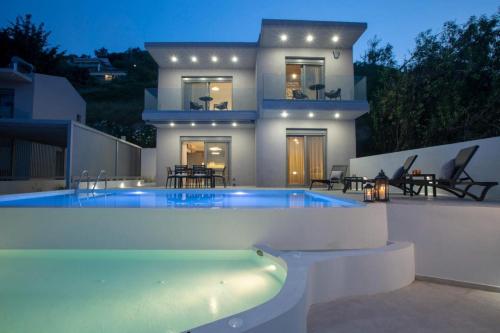 a house with a swimming pool in front of a house at Aloft Luxury Villas Lefkada - Heated pool Lefkia Villa in Apolpaina