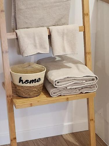 - un porte-serviettes en bois avec des serviettes et un panier dans l'établissement Charmante petite maison de bourg avec spa, à Val Couesnon
