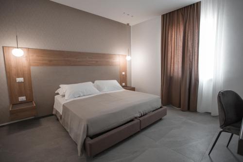 a bedroom with a large white bed and a chair at Alexander House Hotel in San Ferdinando