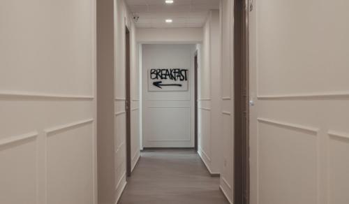 a hallway with white walls and a sign on a door at Alexander House Hotel in San Ferdinando