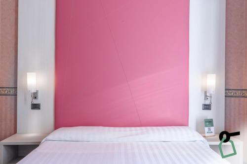 a bed in a room with a pink wall at Hotiday Room Collection - Stresa in Stresa