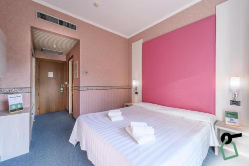 a bedroom with a large bed with a pink wall at Hotiday Room Collection - Stresa in Stresa