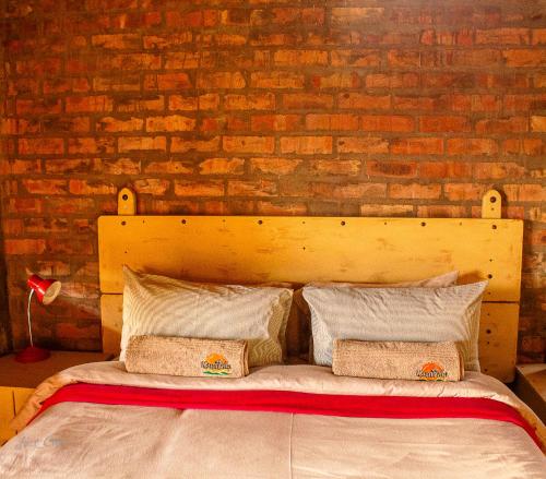 1 cama con 2 almohadas frente a una pared de ladrillo en Kampala Farm, en Bonnievale