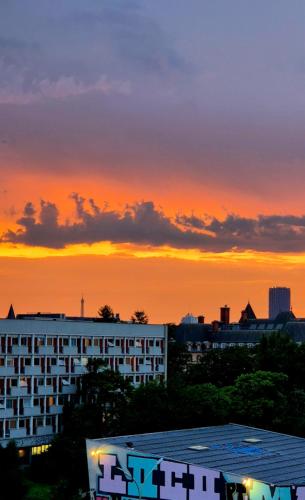 un coucher de soleil sur une ville avec un bâtiment au premier plan dans l'établissement Marvellous Studio Paris 14, à Gentilly
