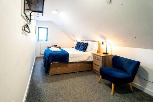 a bedroom with a bed and a blue chair at 3 Bedroom Apartment, Walking Distance to Centre & Amazing Food at your door step in Cardiff