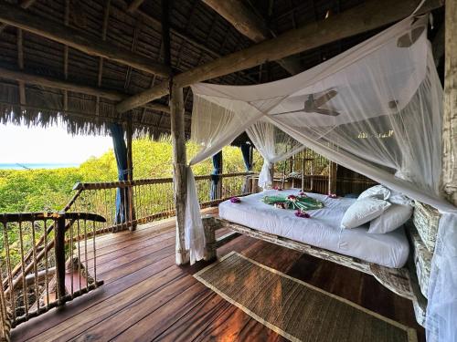 a bed in a room with a hammock on a deck at Chole Mjini Treehouses Lodge in Utende