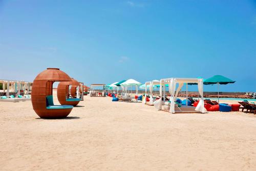 a row of beach chairs and umbrellas on a beach at Gewan Palace New Alamein in El Alamein