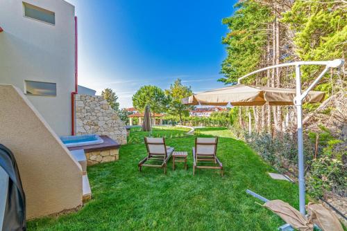 a backyard with two chairs and an umbrella at Pelagus Luxury Villas in Polykhrono