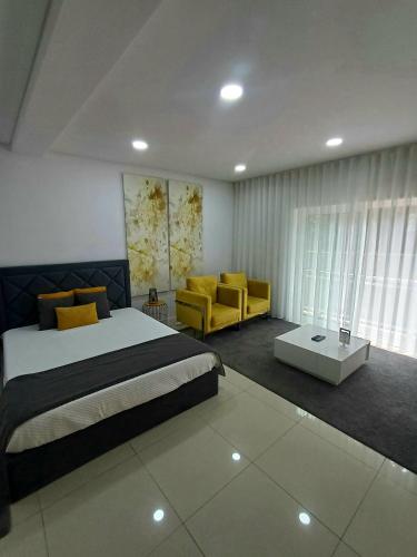 a bedroom with a bed and two yellow chairs at Villa Barrinha in Praia de Mira