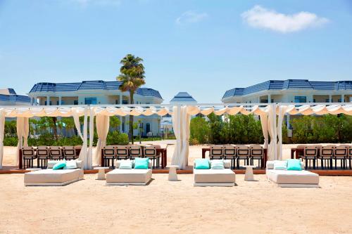a beach with chairs and umbrellas in front of a building at Gewan Palace New Alamein in El Alamein